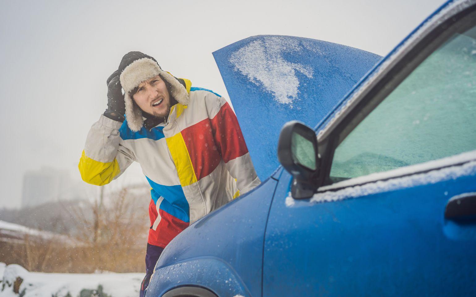 雪道の車の故障に困る男性