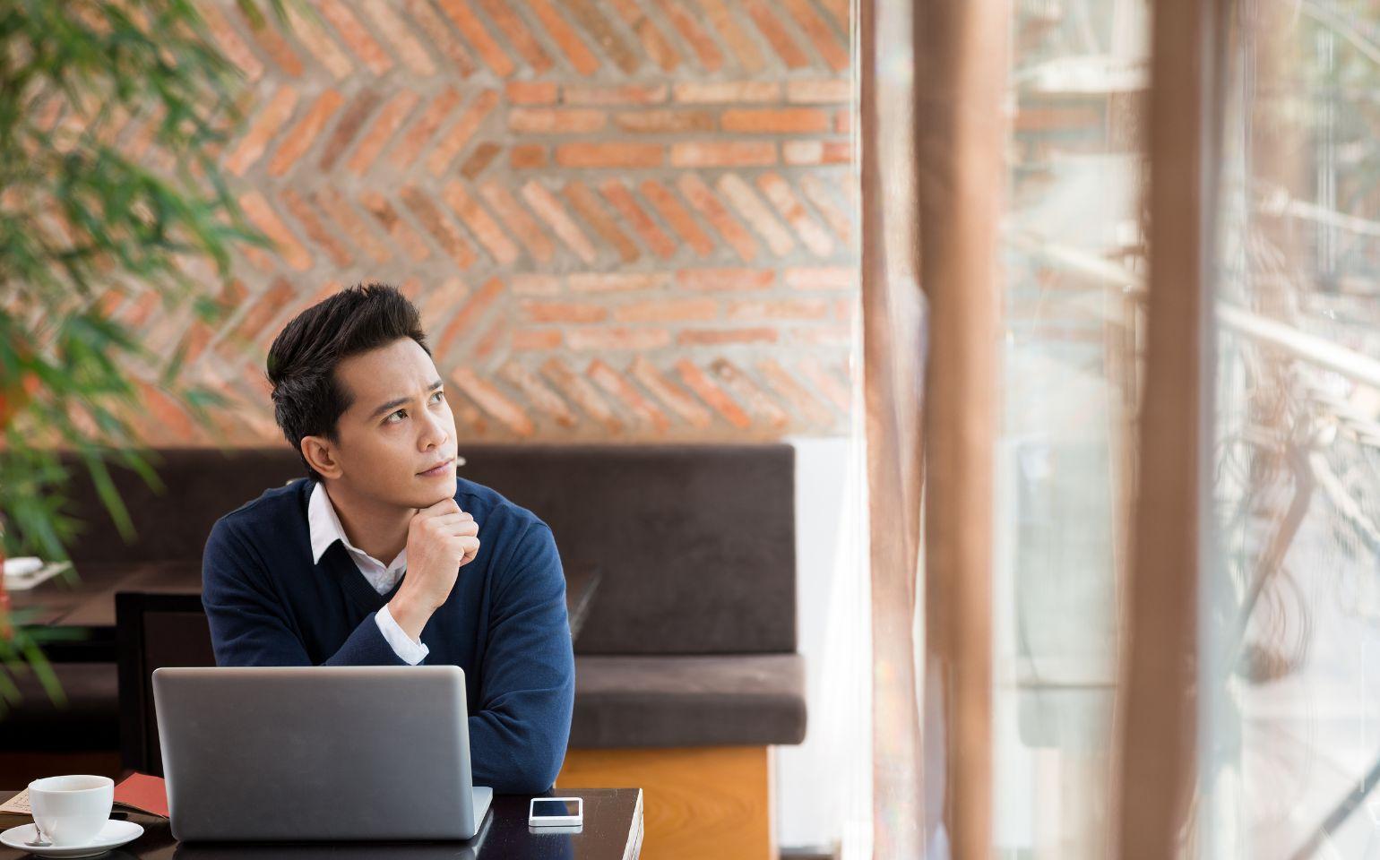 パソコン作業しながら外を眺めるビジネスマン